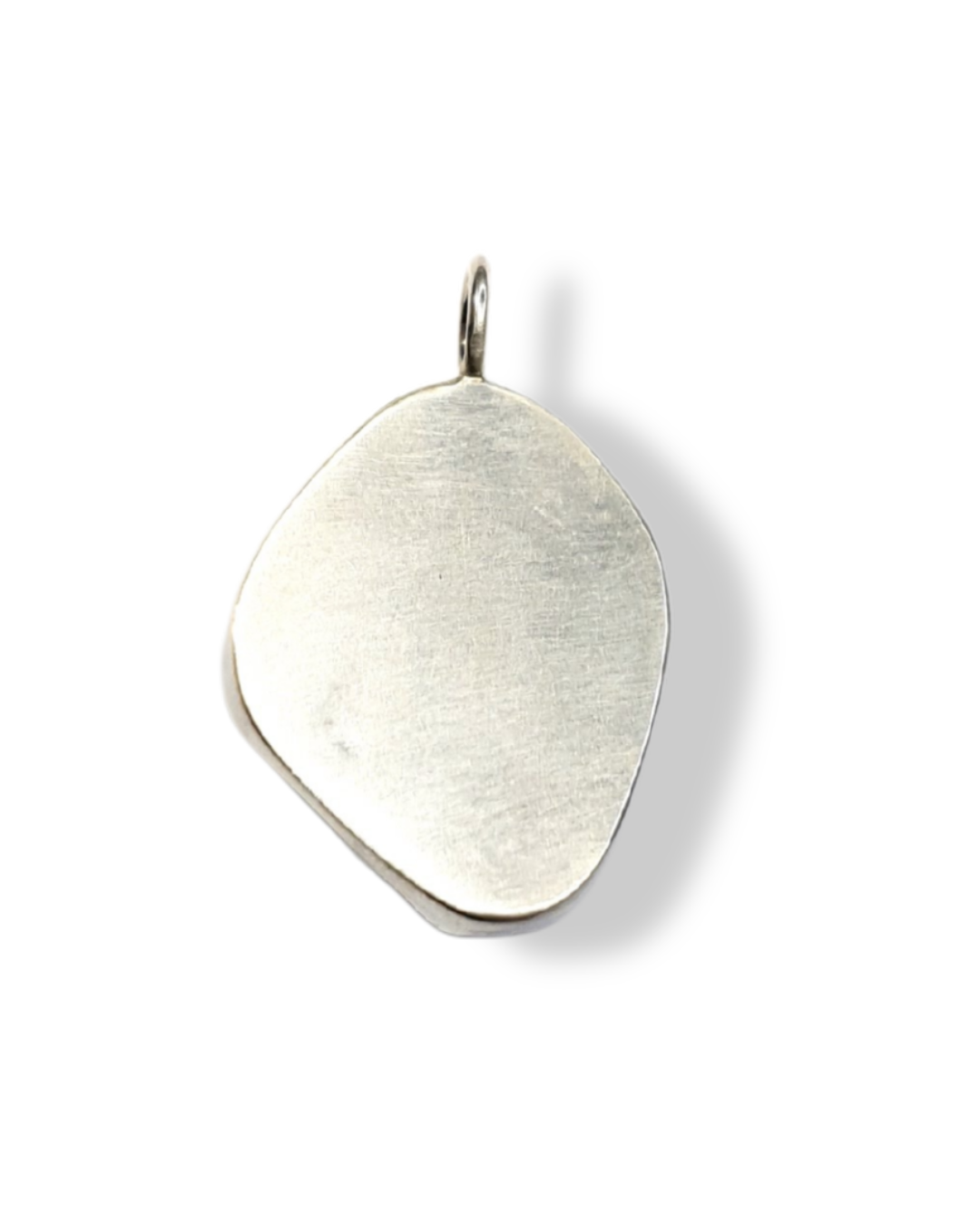 The back of a pendant is photographed from above on a white background. All that is visible is a flat, irregular, silver shape and a round bail at the top.