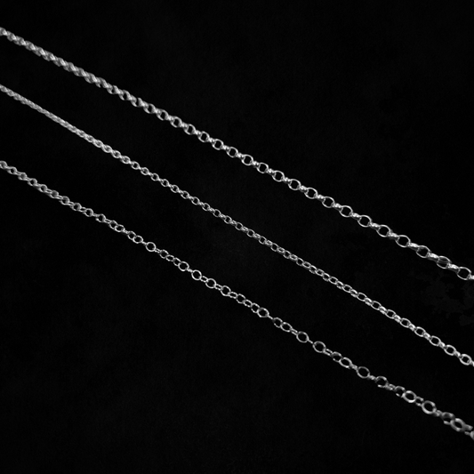 Three different types of chain are laid out against a black background.
They are laid from thickest at the top to thinnest at the bottom demonstrate the difference in link size and thickness.