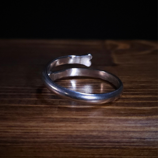An open style bone ring sits on a wooden surface. It's photographed from the back to show that the inside is smooth and comfortable to wear.