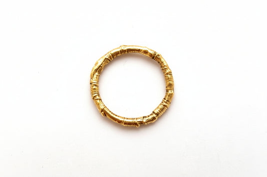 A twig ring made of 9ct yellow gold sits on a white background