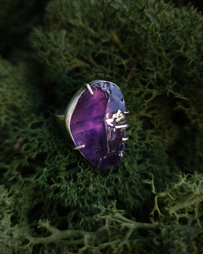 A deep purple amethyst ring sits nestled in some rich green moss. It has an alternative, witchy and unisex style.