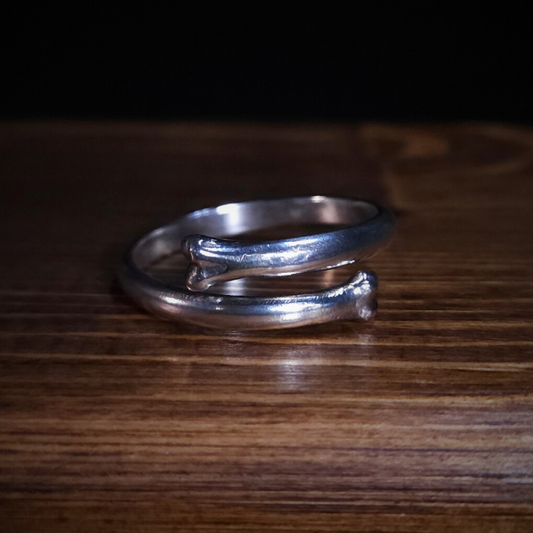 An open style bone ring sits on a wooden surface.