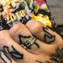 Load image into Gallery viewer, A tattooed hand wears 2 silver rings with the words &quot;black sheep&quot; stamped into them
