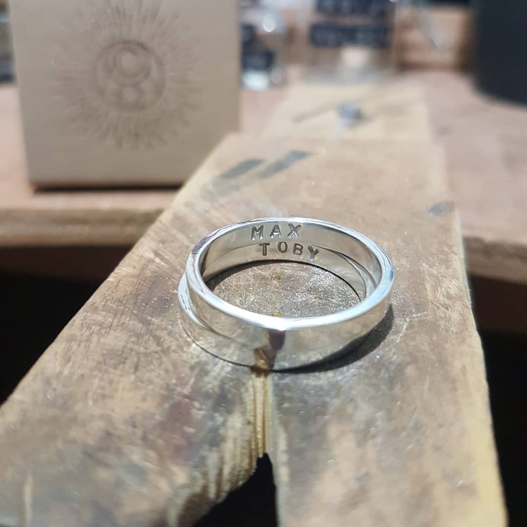 2 rings sit stacked on my workbench. The names "Max" and "Toby" are stamped on the inside of the rings..