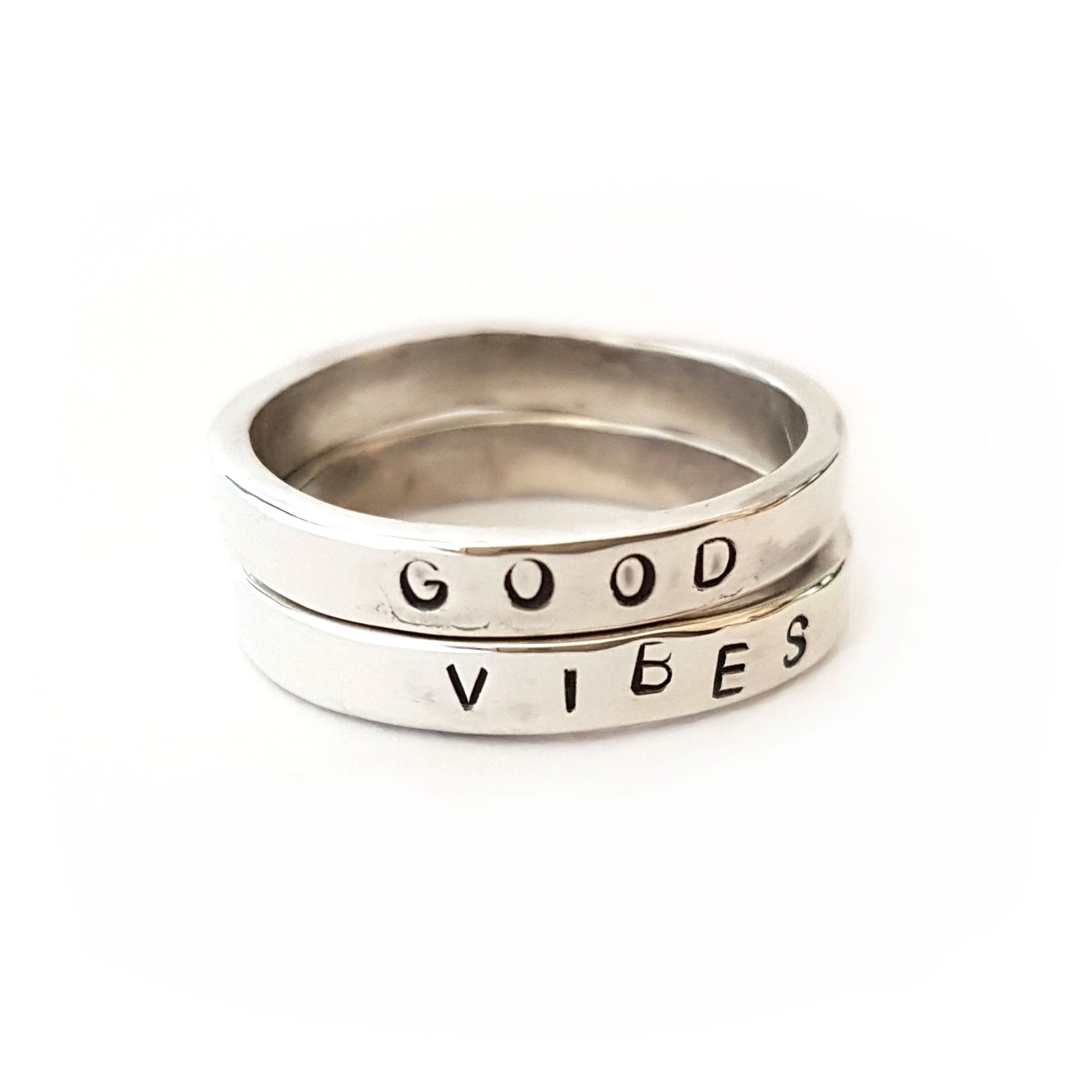 2 silver rings with the words "good vibes" stamped into them