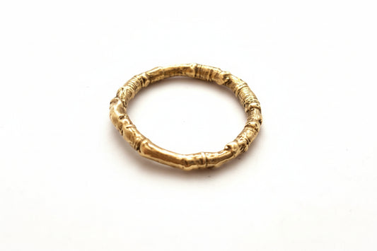 A twig ring made of 9ct yellow gold sits on a white background