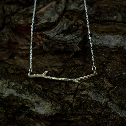 Bronze woodland necklace on a dark, bark background