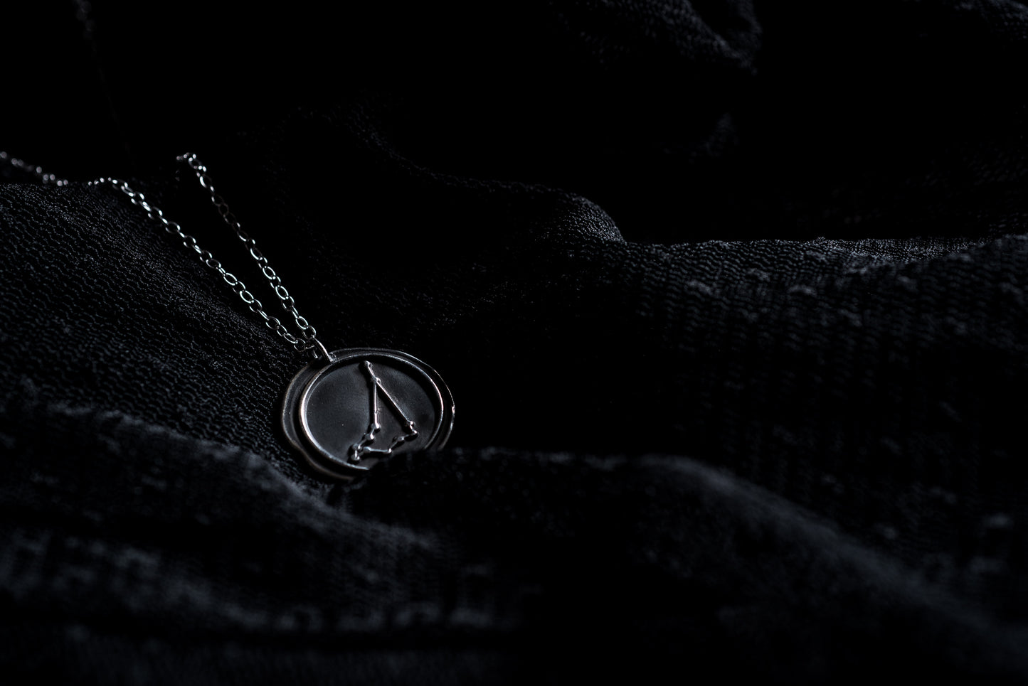 Capricorn zodiac necklace resting against a black background